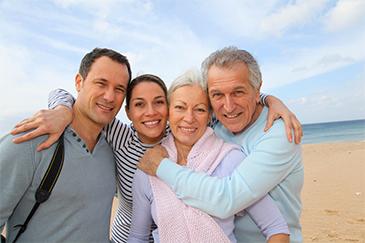 mother, father, son, and daughter in law smiling on beach