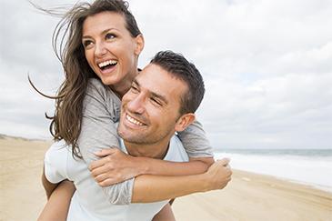man and woman smiling on the beach