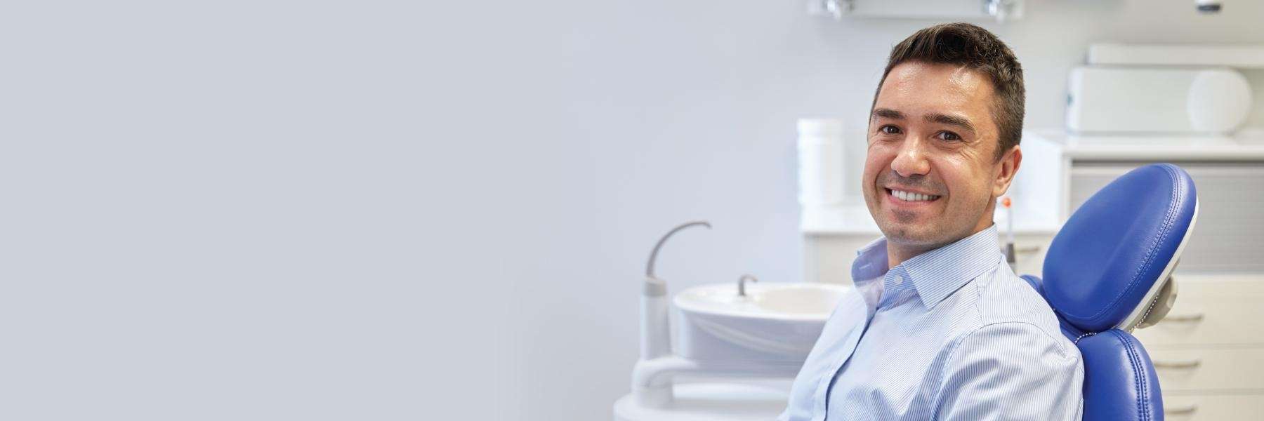 man sitting in a blue dental chair