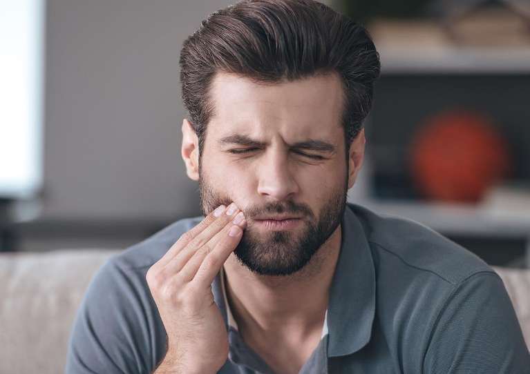 man holding jaw from pain during a dental emergency