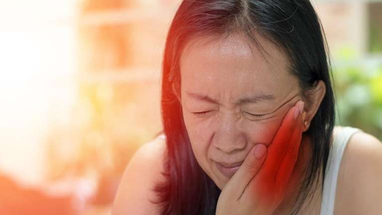 Woman holding her cheeks to calm down during dental emergegncy