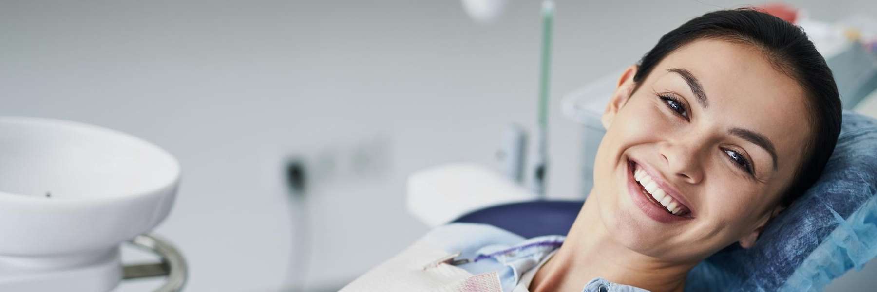 woman sitting in a dental chair while smiling